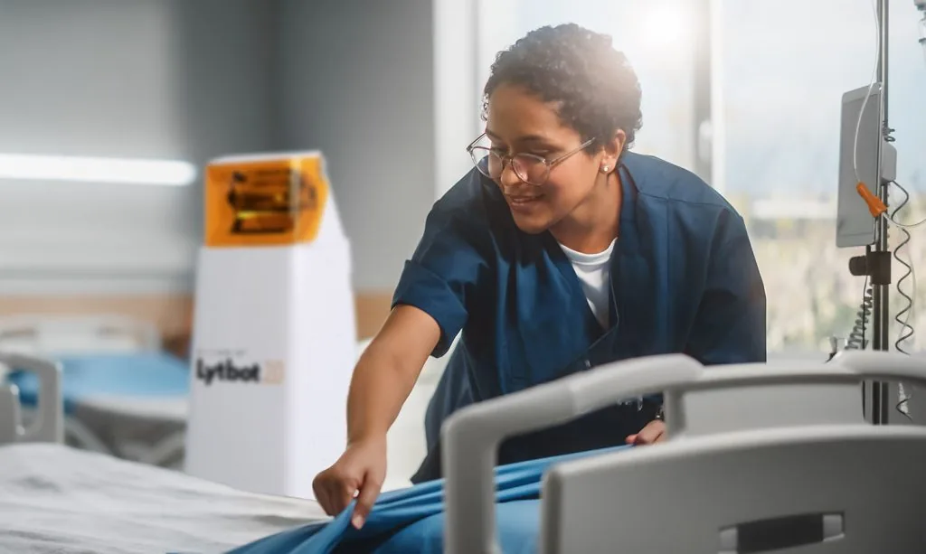 A healthcare professional preparing a patient room with Lytbot 2.0 nearby